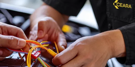 Mãos de um técnico da Ceará organizando os fios de um chicote elétrico